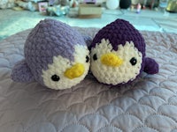 two crocheted penguins sitting on a bed